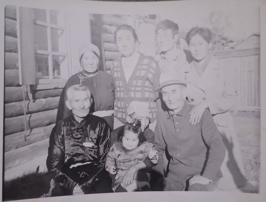 Original washed-out family snapshot outside a log house